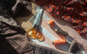 Scissors and spools of thread on fabric.