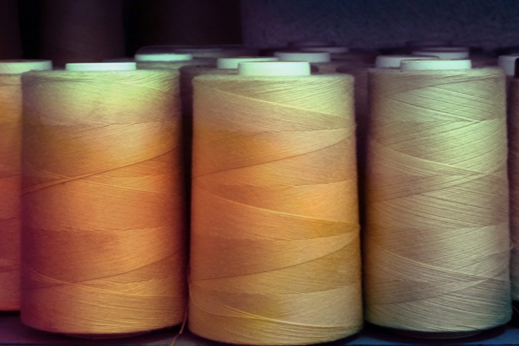 Cones de linha sobre tecido em bancada de trabalho